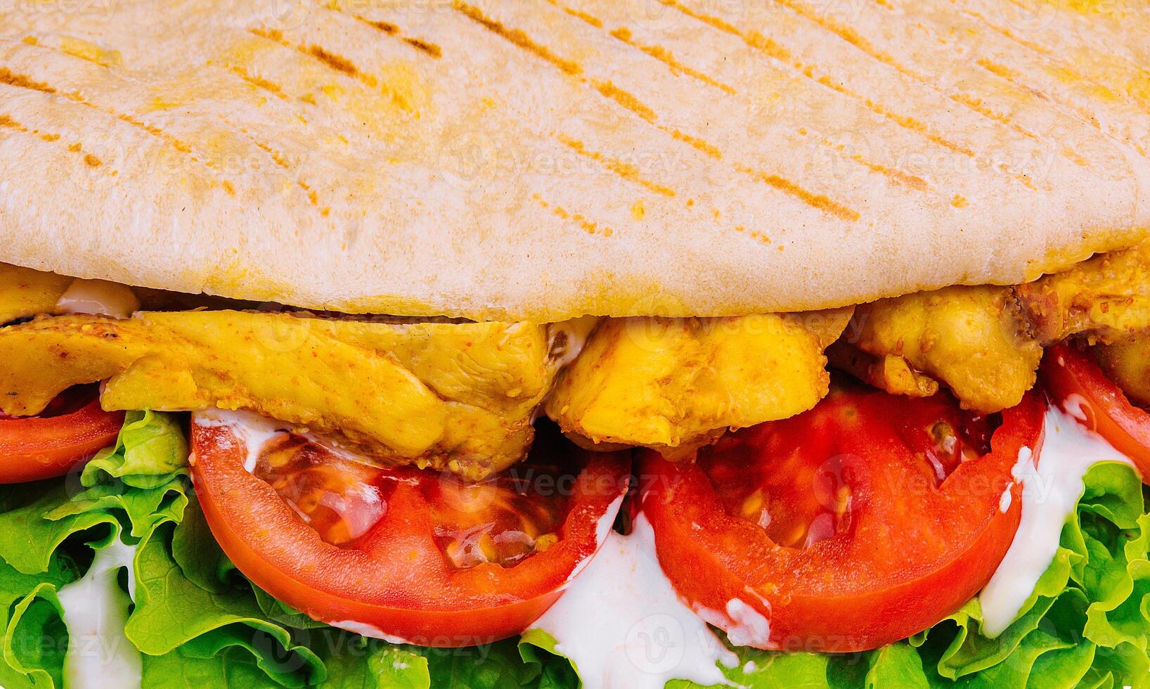 Close-up view of a delicious grilled chicken panini with fresh vegetables photo