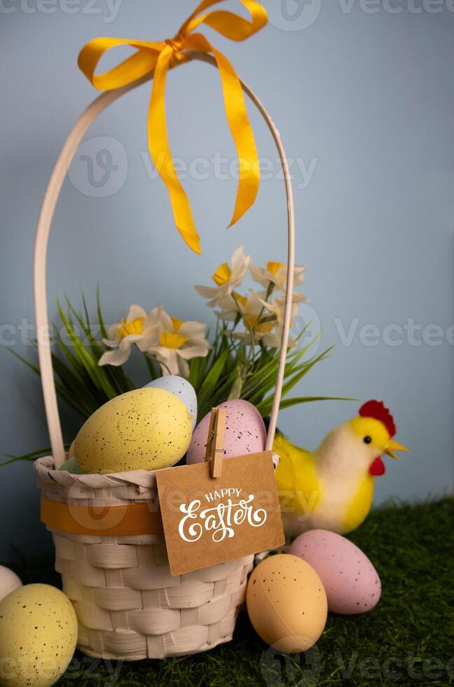 Vertical Easter card with basket full of pastel colorful eggs daffodil flowers chicken photo