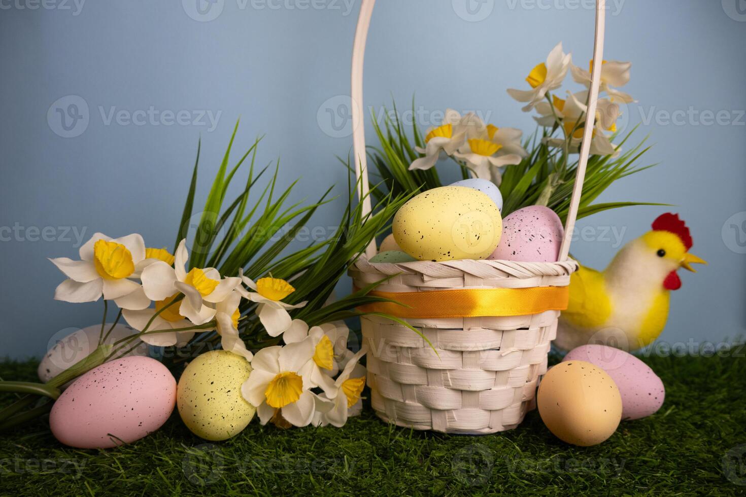 Easter card with white basket with pastel colorful eggs daffodil flowers on a blue background photo