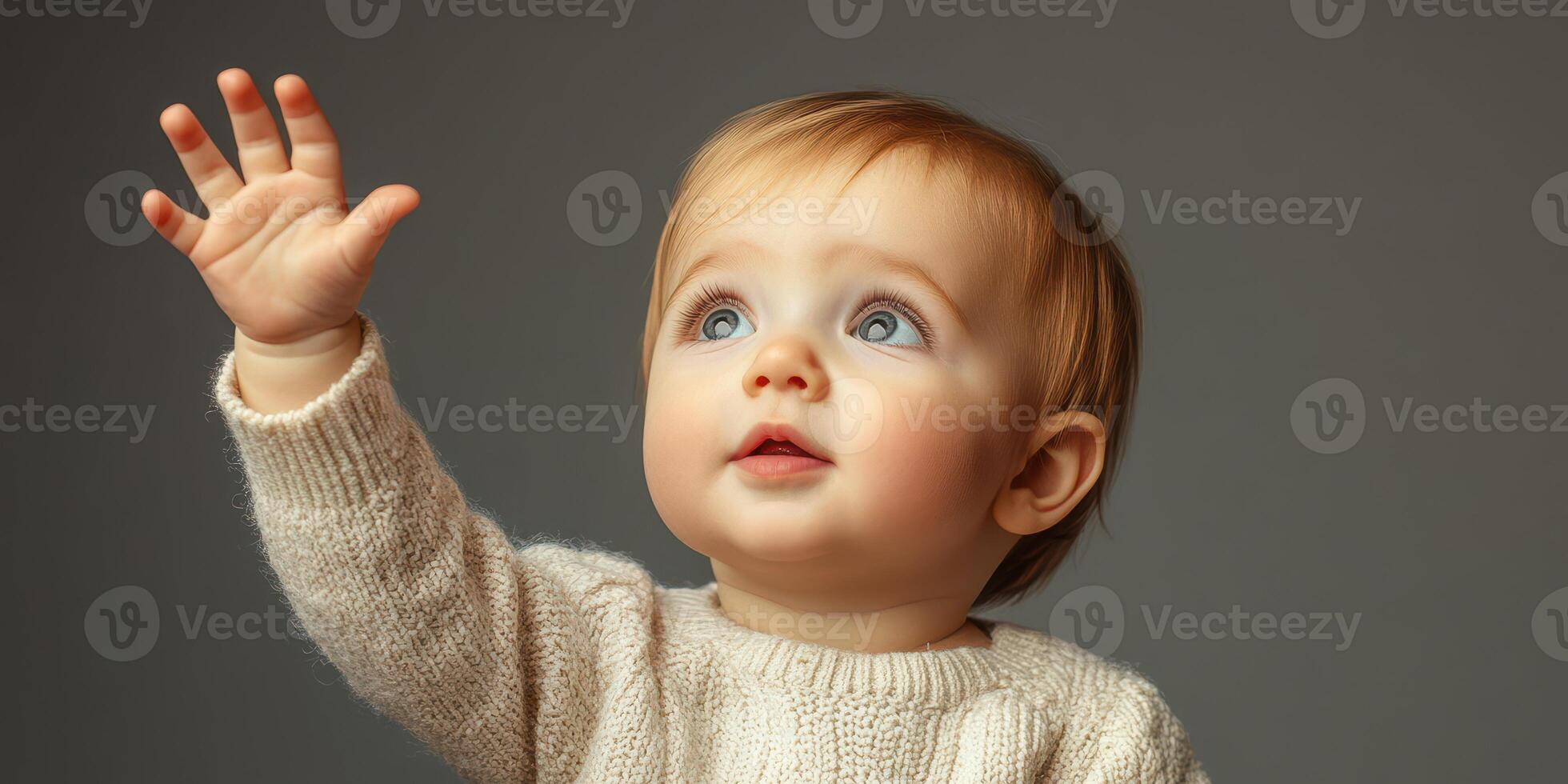 Baby with blue eyes reaching up excitedly while wearing a cozy sweater in a softly lit indoor setting photo
