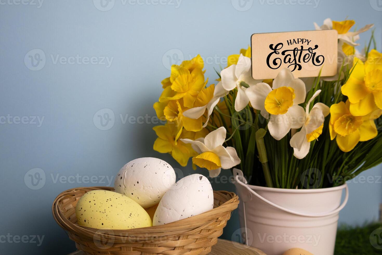 Happy Easter card with daffodil flowers in a white bucket and eggs in a twigs basket photo