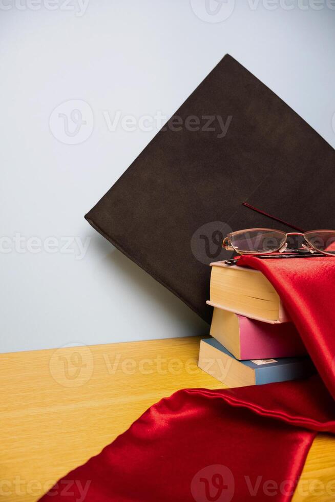 Vertical background of academic hat graduation stole on a stack of books photo