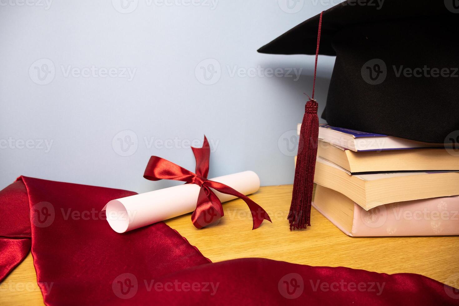 Academic hat stole diploma with red ribbon and stack of books photo