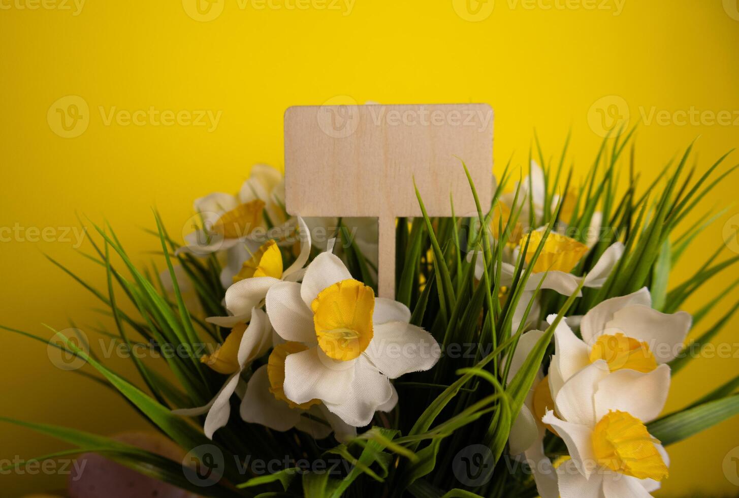 Wooden sign for text and daffodil flowers on a yellow background photo