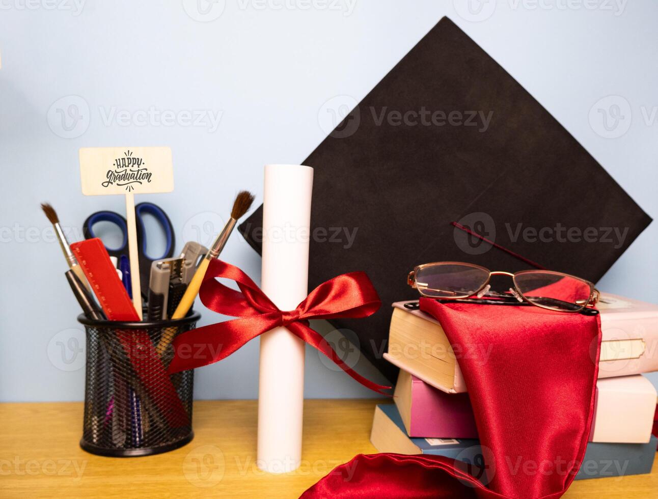 Graduation background with academic hat pen holder diploma with red ribbon eyeglasses and stole on a stack of books photo