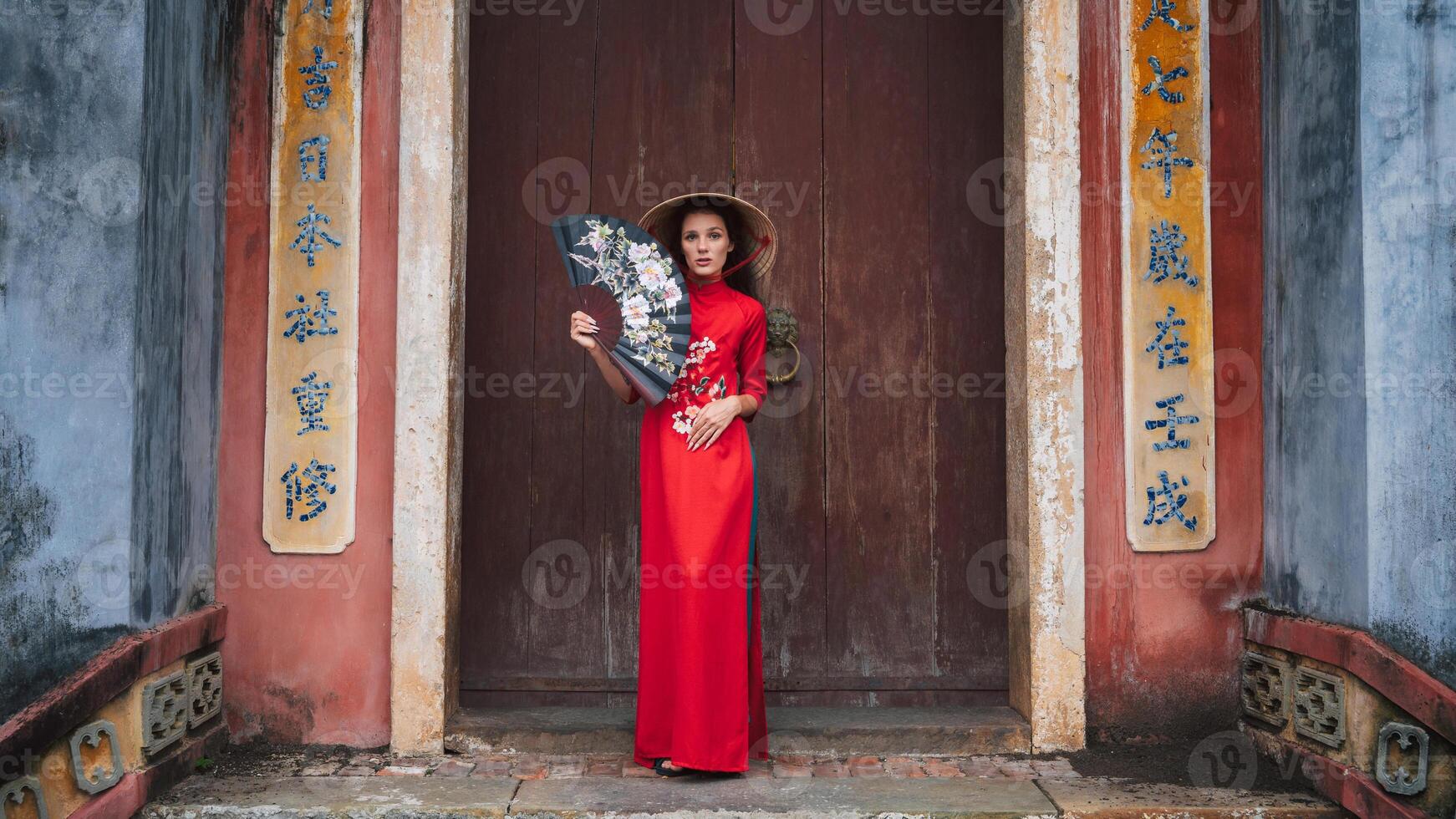 female traveler visiting asia. tourist in hat and traditional vietnamese dress visiting oriental buddhist temple in Hoi an photo