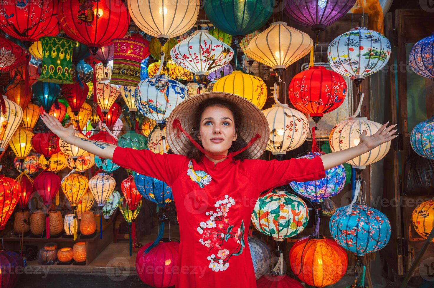 Tourists in traditional Vietnamese clothing look at lanterns in Hoi An ancient town. photo