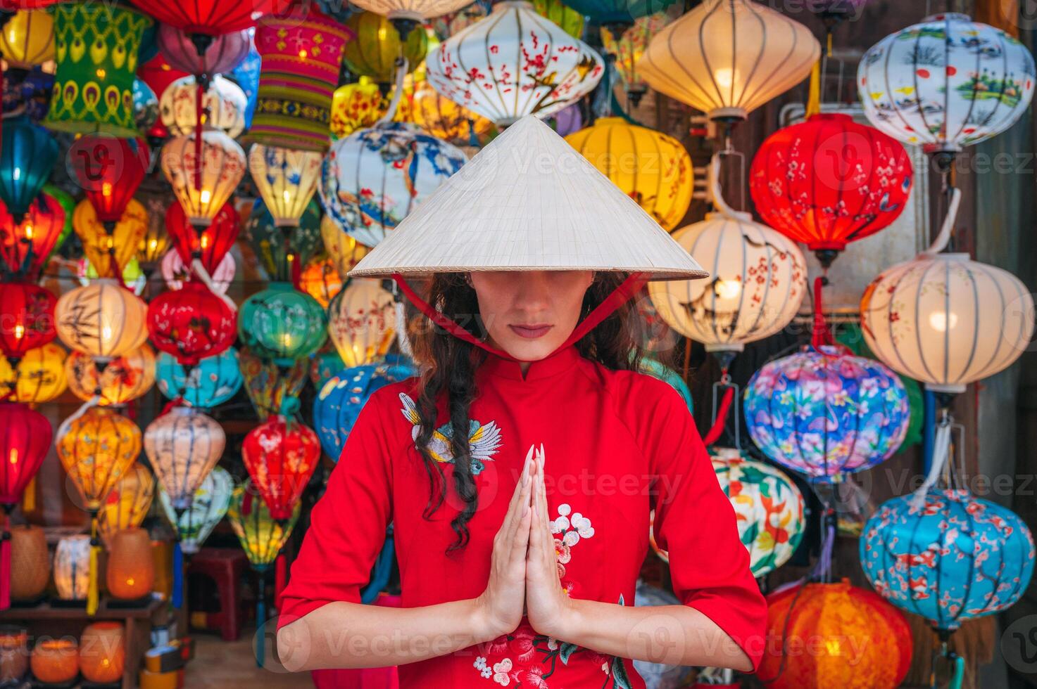 A woman in traditional Vietnamese clothes and a Non La hat on the background of lanterns in the ancient city of Hoi An. photo