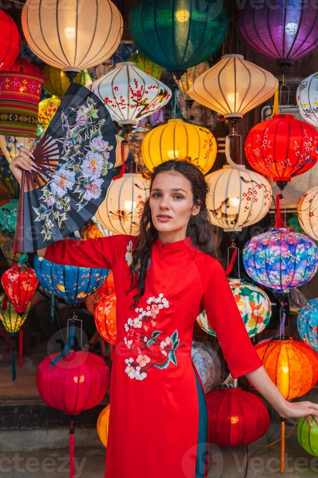 A woman in traditional Vietnamese clothes against the background of lanterns in the ancient city of Hoi An photo