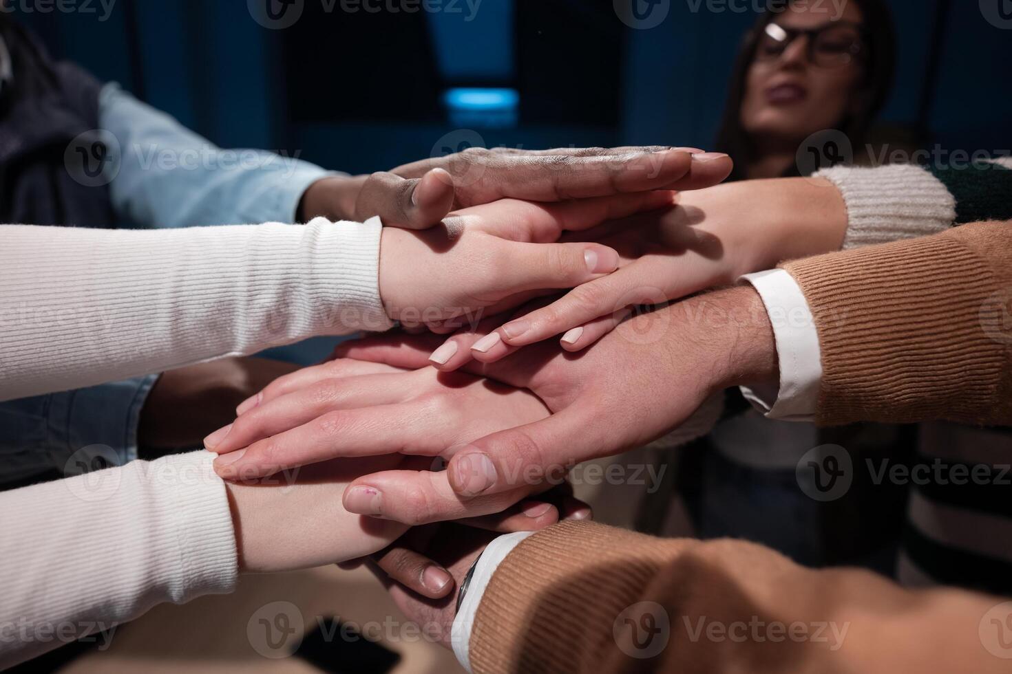 Business professionals stacking hands in support of collaboration, inclusion, and equality in the office. The workplace community huddles together for solidarity, cooperation, and team building. photo