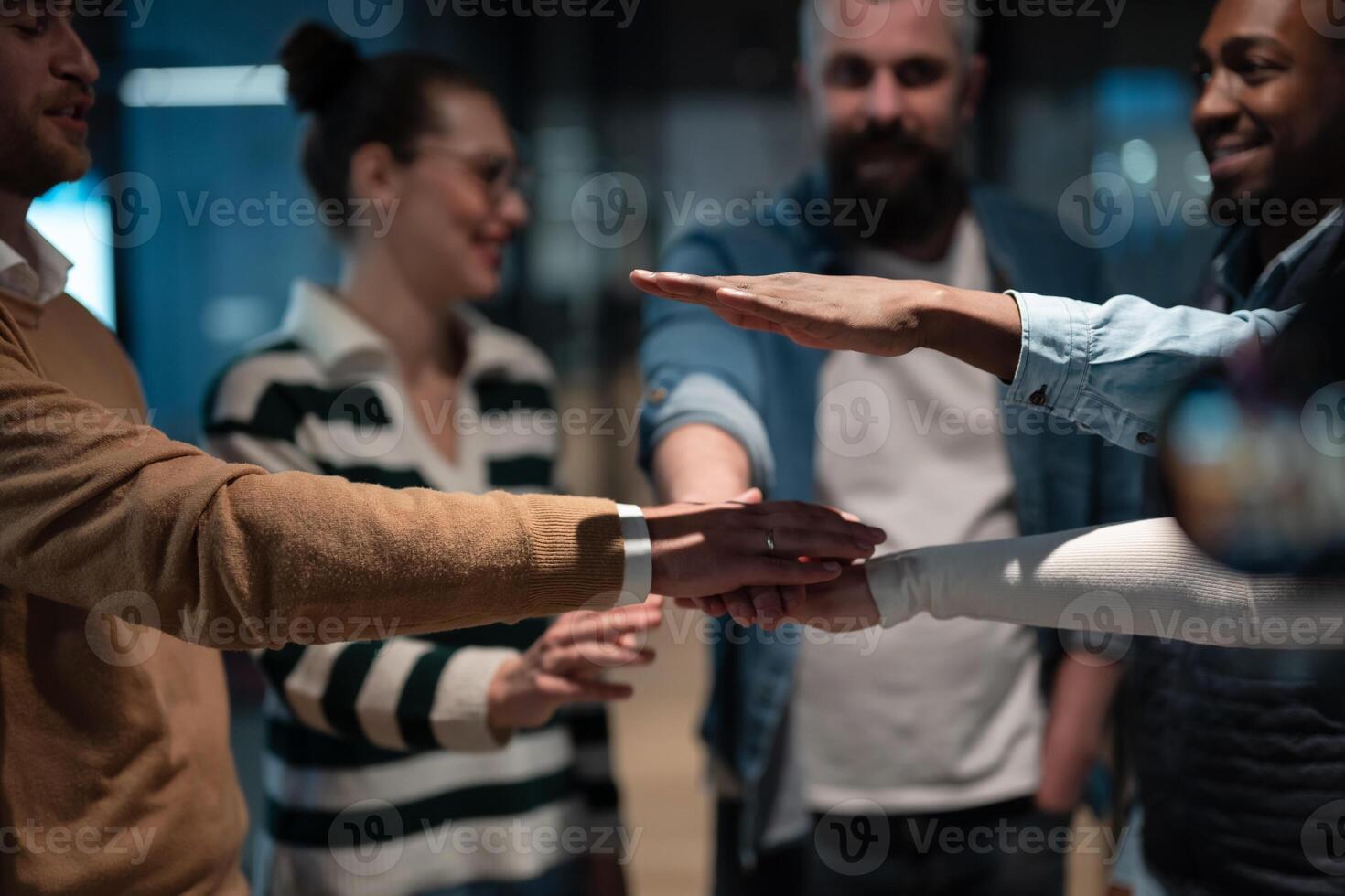 Business professionals stacking hands in support of collaboration, inclusion, and equality in the office. The workplace community huddles together for solidarity, cooperation, and team building. photo