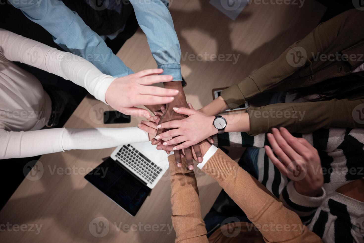 Business people team stacking hands to promote collaboration, inclusion, and equality in the office. Staff huddles together, concept of solidarity, cooperation, and teamwork in a supportive workplace. photo