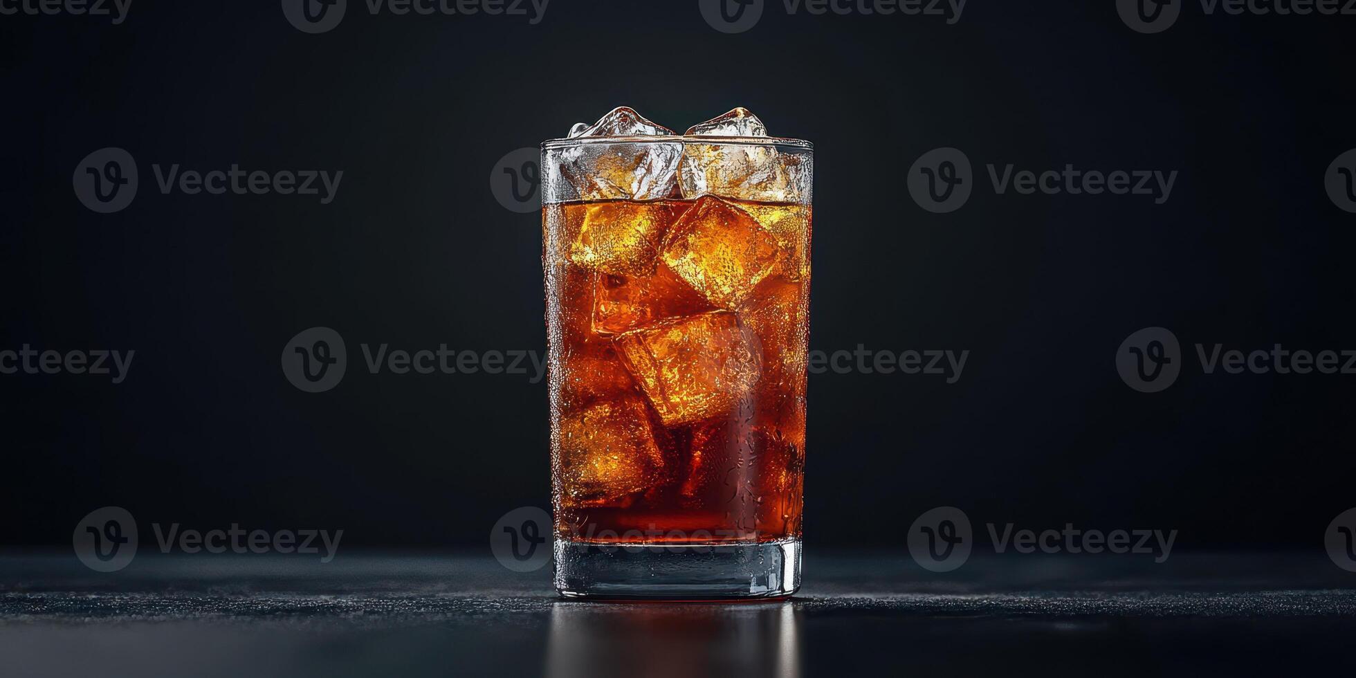Refreshing beverage served in a clear glass with ice cubes against a dark background photo