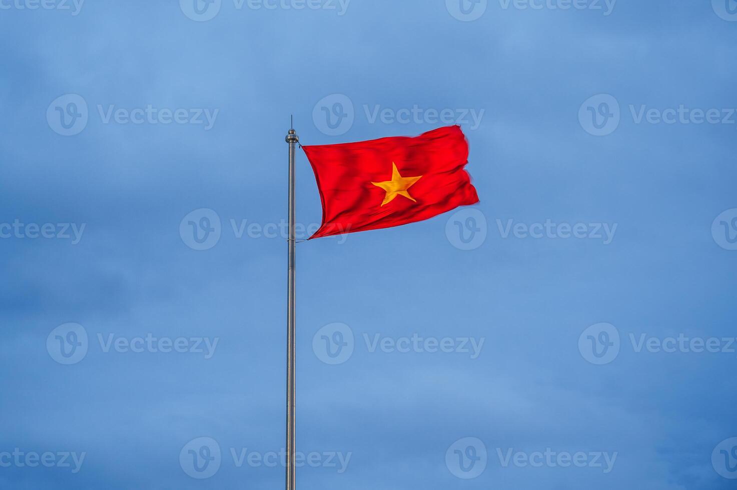 Vietnamese flag waving in the wind with clear blue sky. Yellow star on red background. photo