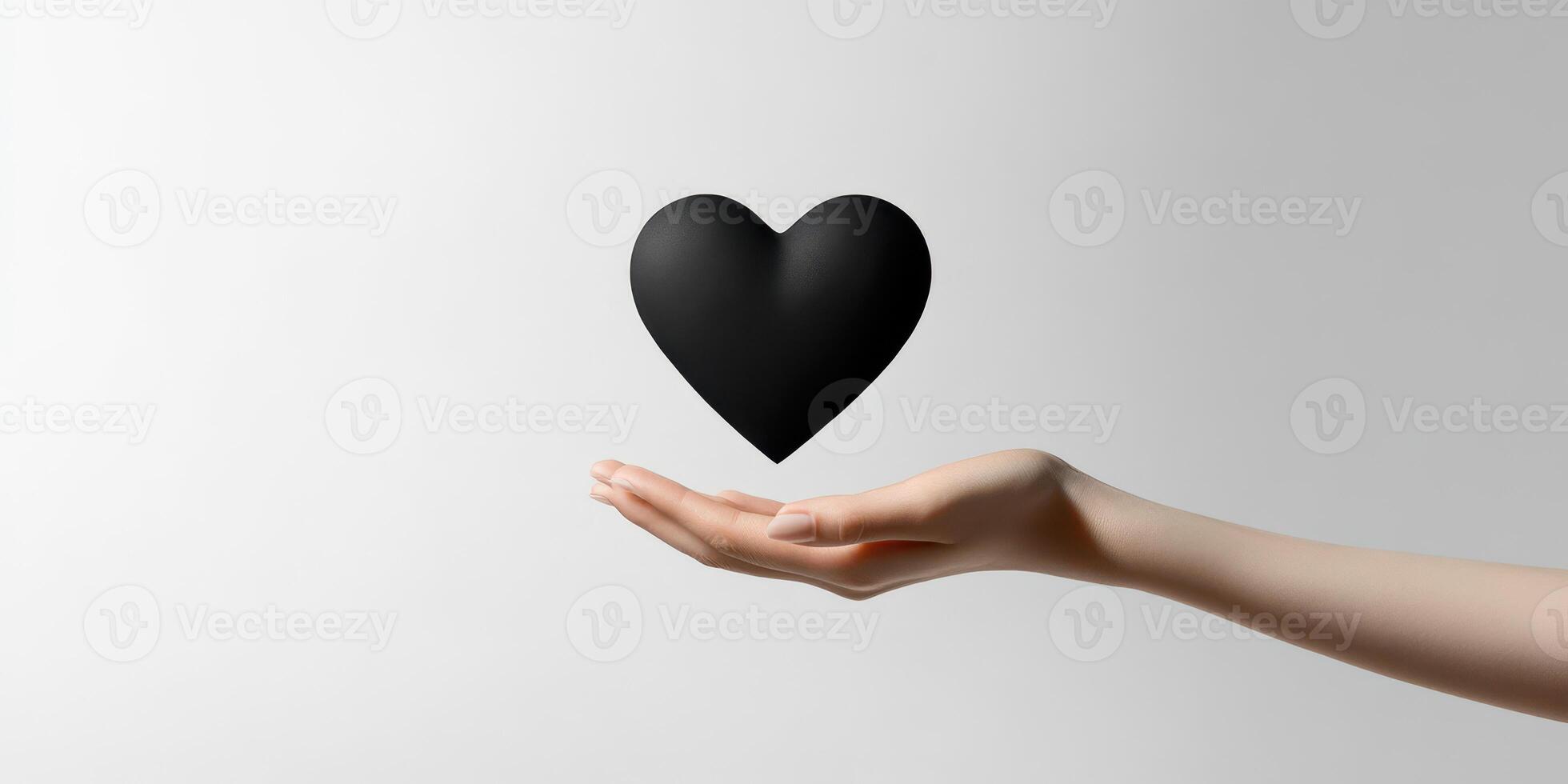 Black heart being held softly in an open hand against a minimalist background photo