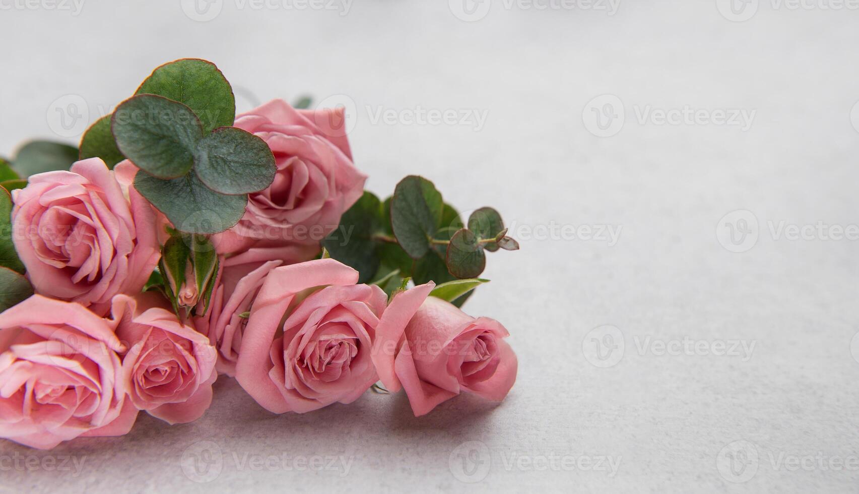 Pink roses and eucalyptus leaves forming a beautiful bouquet on a textured surface photo
