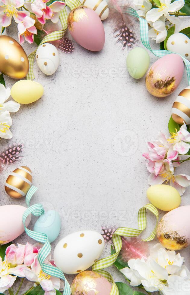 Easter eggs frame on a gray background with flowers and feathers photo