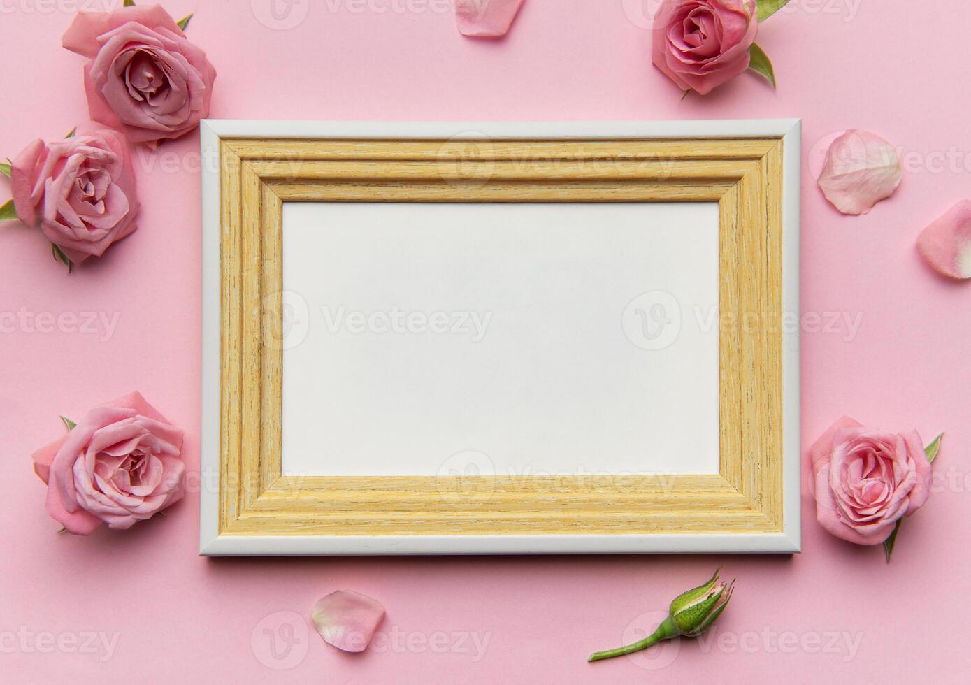 Empty frame surrounded by pink roses and petals on pink background photo