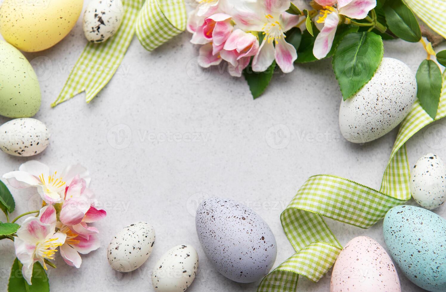 Easter eggs and spring flowers creating a frame on a gray background photo