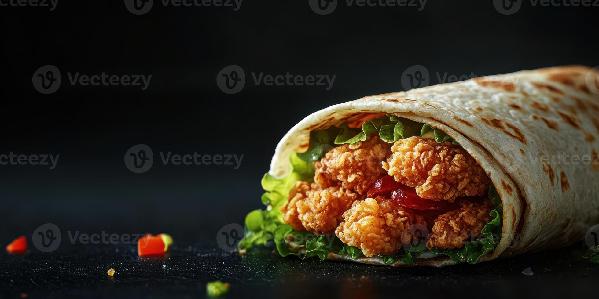 Crispy chicken wrap with fresh lettuce and tomatoes served on a dark background photo