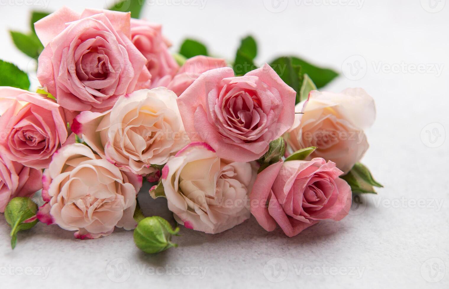 Delicate pink and peach roses forming a beautiful bouquet on a textured surface photo