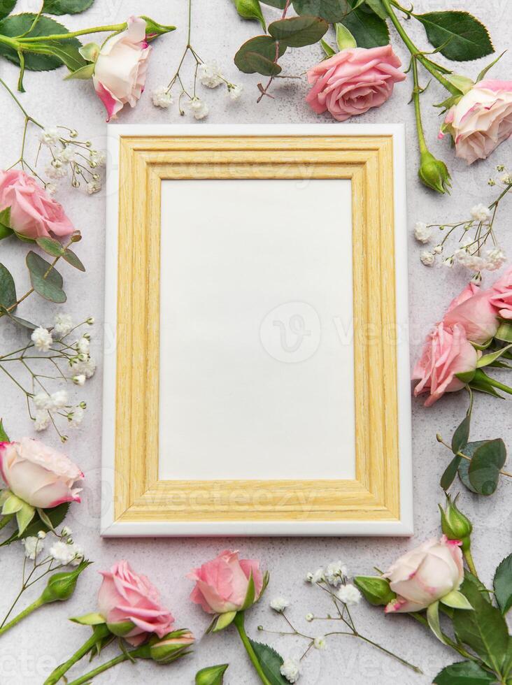 Empty frame with pink roses and eucalyptus on grey background photo