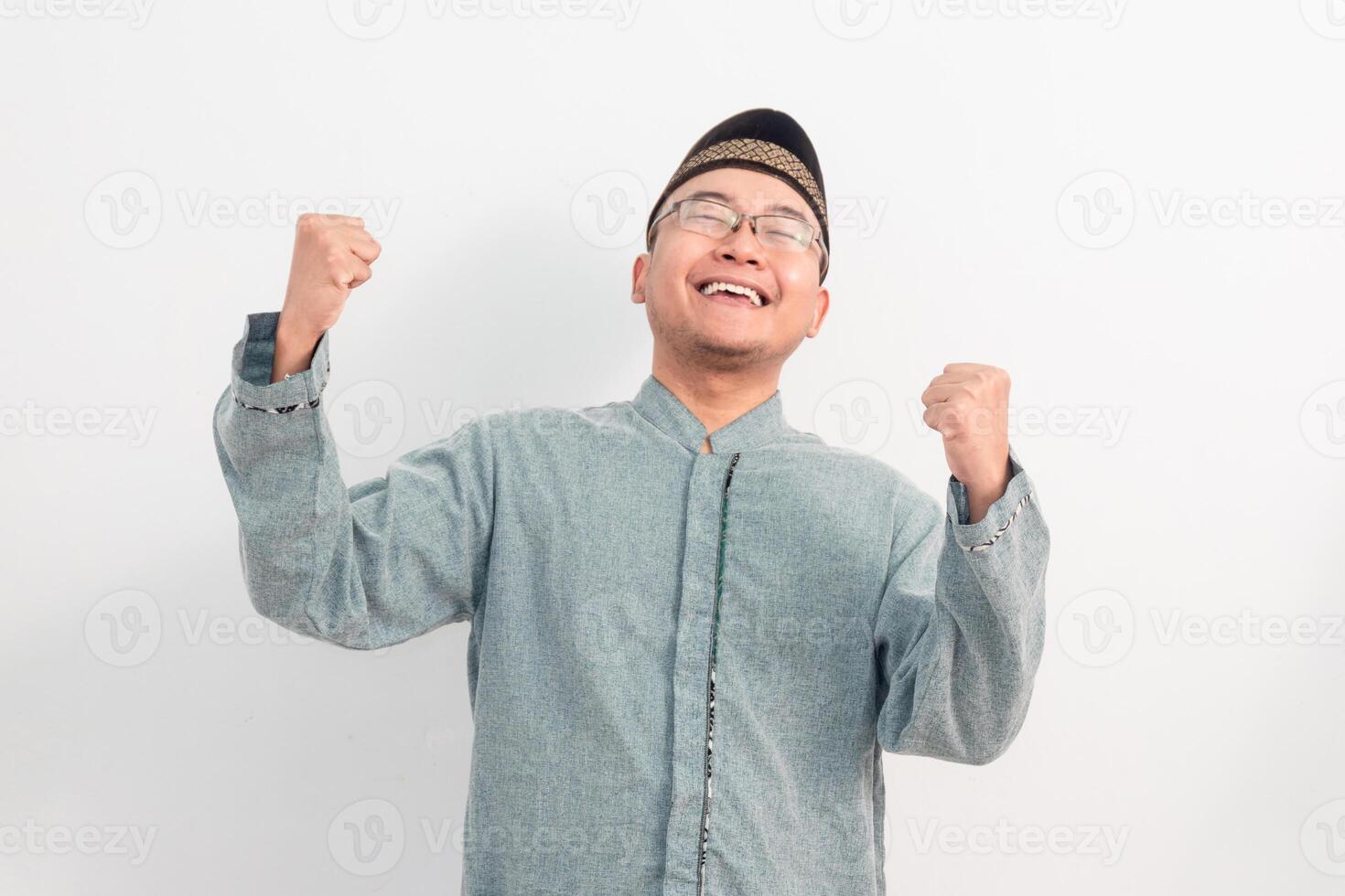 Cheerful Asian Muslim man smiling doing successful gesture in Ramadan Eid Al Fitr and eid adha days celebration isolated white background. Islamic celebration concept. photo