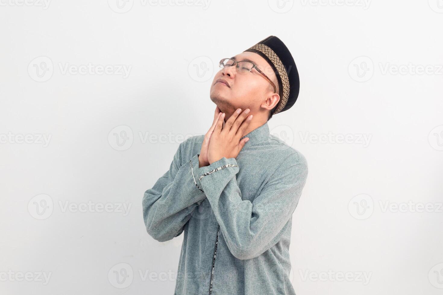 Hurtful Asian Muslim man touching neck, thirsty gesture during fasting in Ramadan Eid Al Fitr and eid adha days celebration isolated white background. Islamic celebration concept. photo