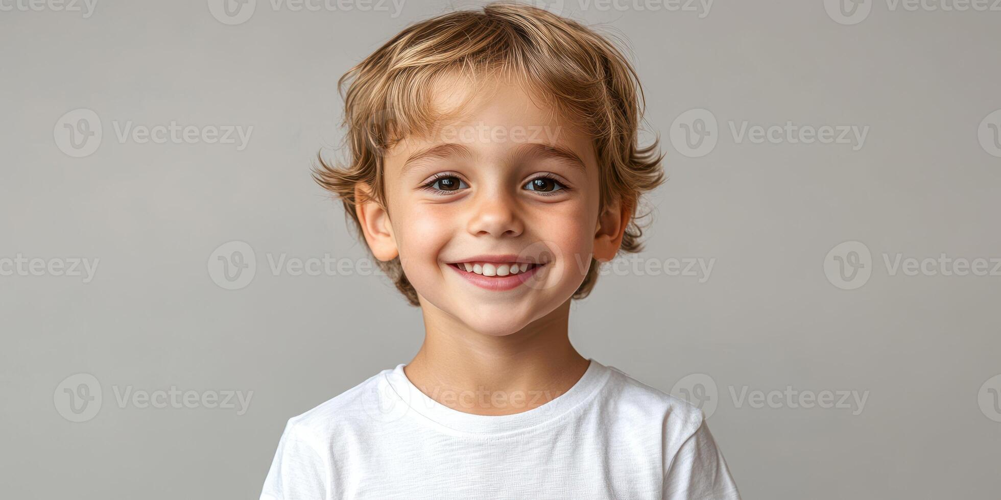 Young boy with joyful smile against a plain backdrop in a bright setting photo