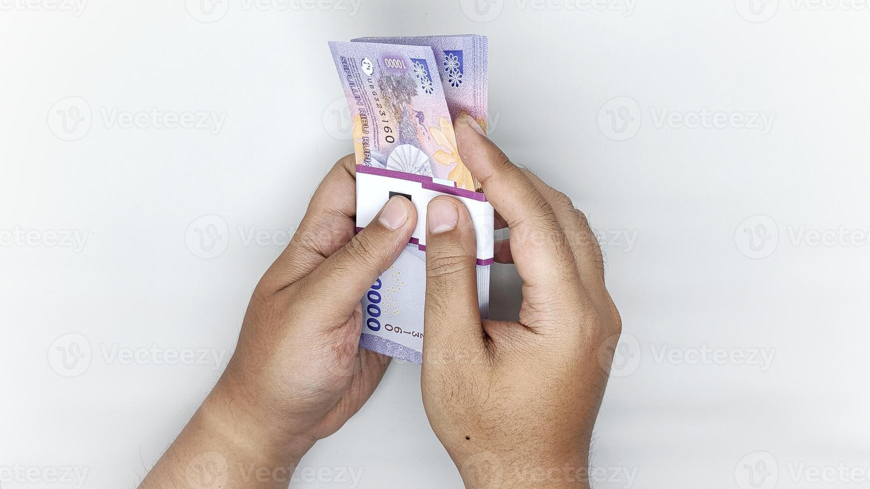 two hands counting Indonesian banknotes in the 10,000 rupiah denomination photo