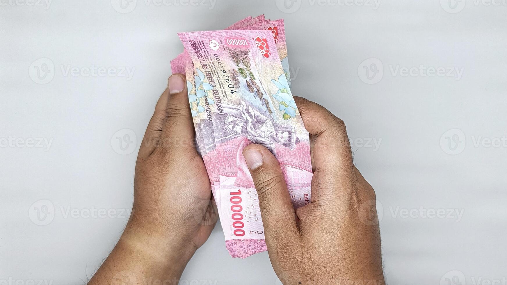 two hands counting Indonesian banknotes in the 100000 rupiah photo