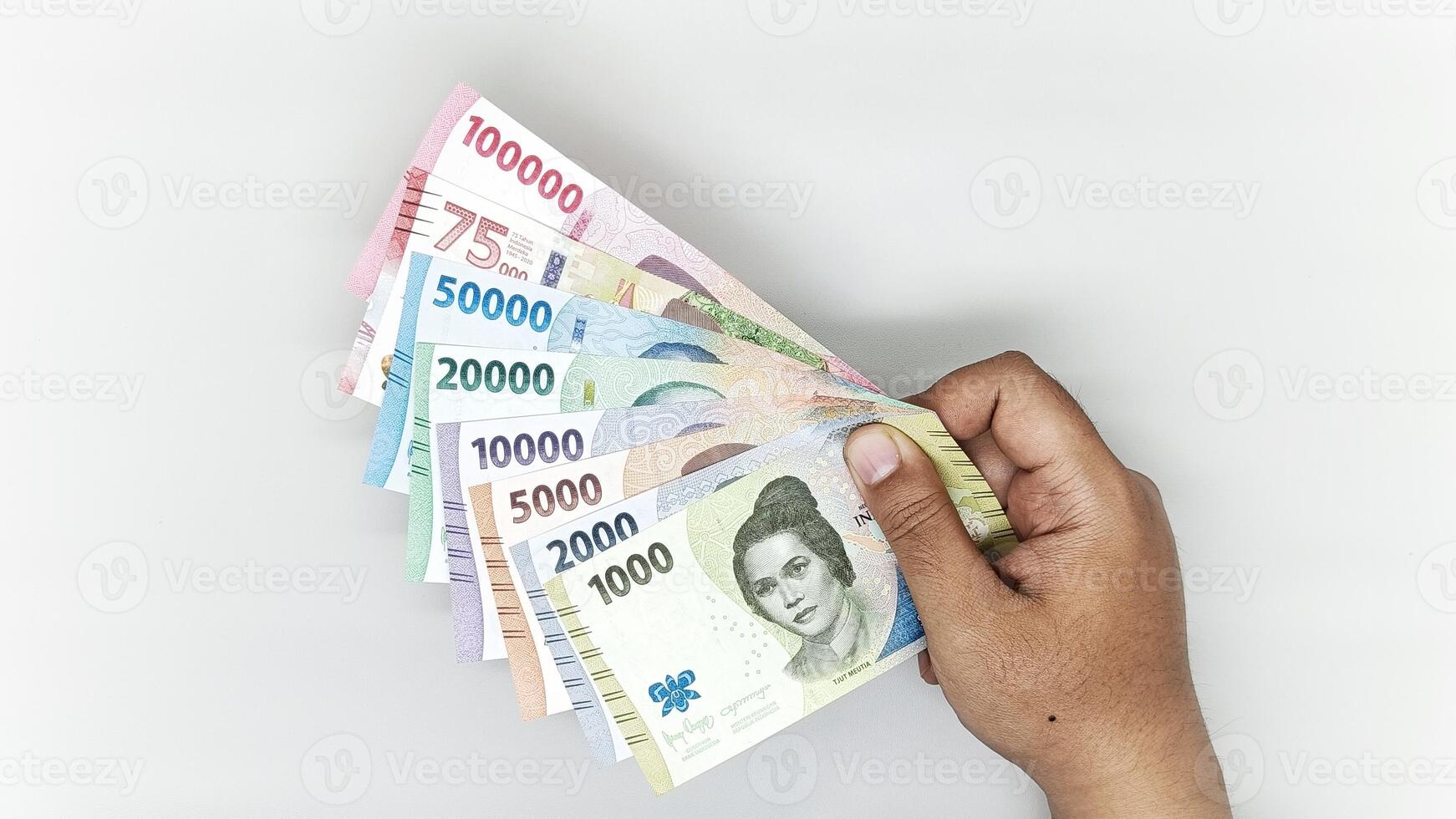 hand holding a collection of Indonesian banknotes in denominations 1000, 2000, 5000, 10000, 20000, 50000, 75000, 10000 rupiah photo
