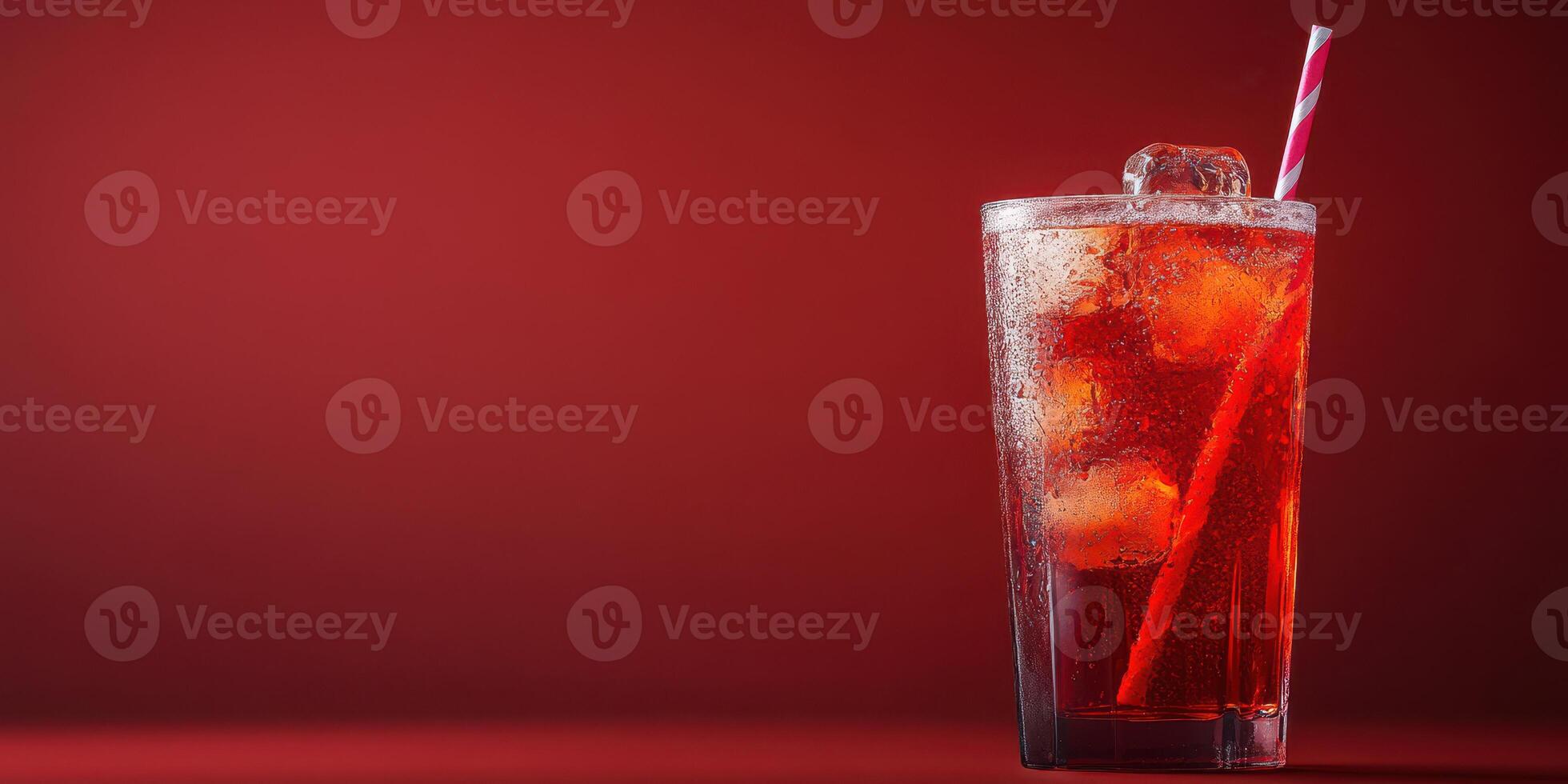 Refreshing iced beverage with ice cubes and a straw on a vibrant red background photo
