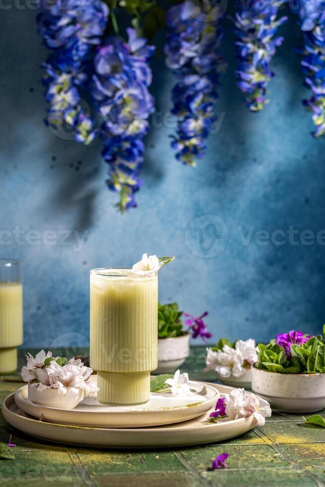 Refreshing iced matcha latte garnished with a delicate flower and mint leaf, served on a stylish table setting photo