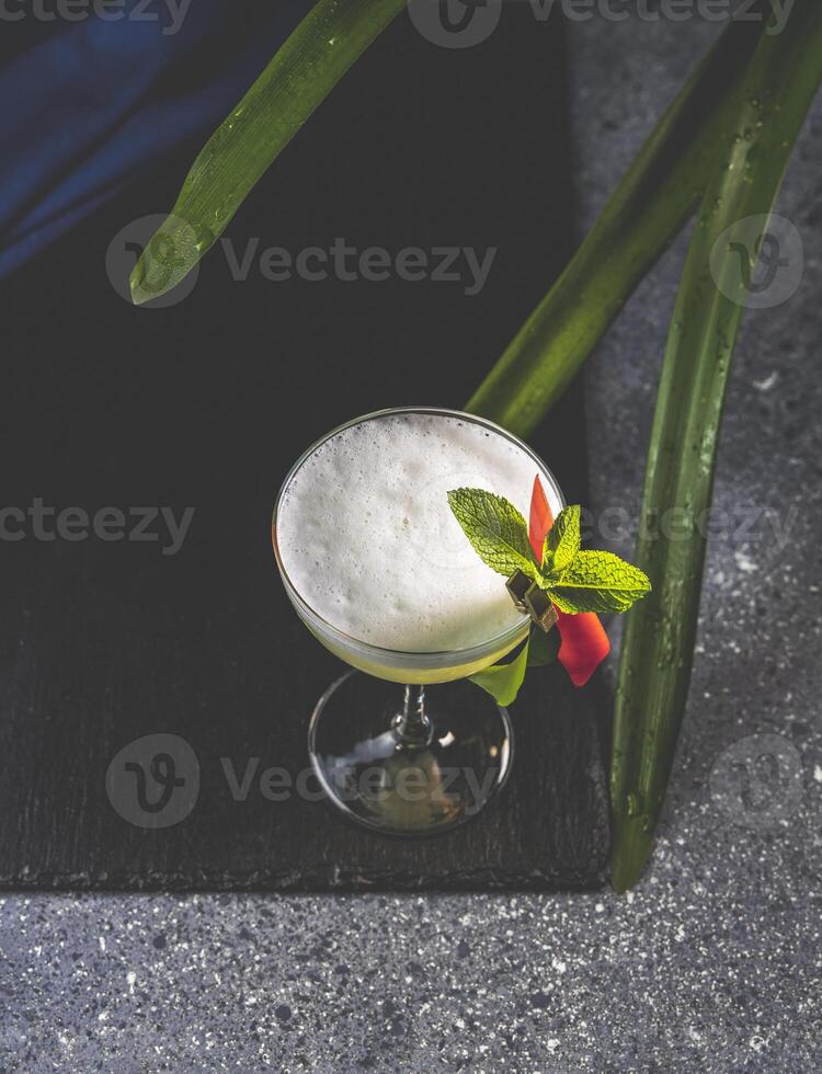 Refreshing pisco sour cocktail decorated with mint and exotic flower photo