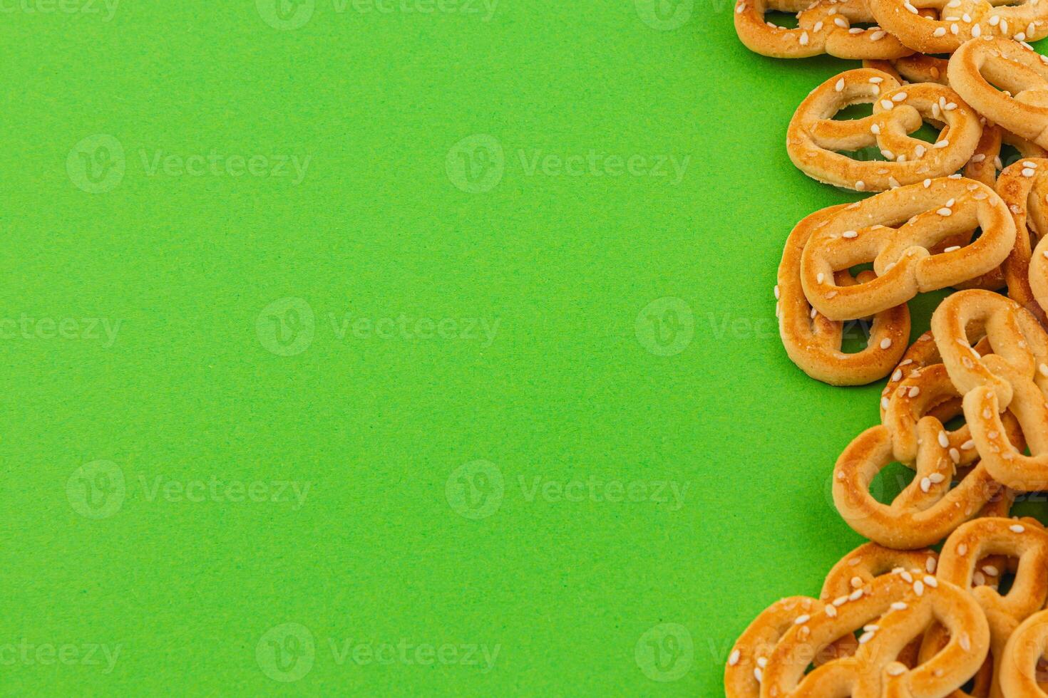 Crispy pretzels scattered on a vibrant green background for snacking photo