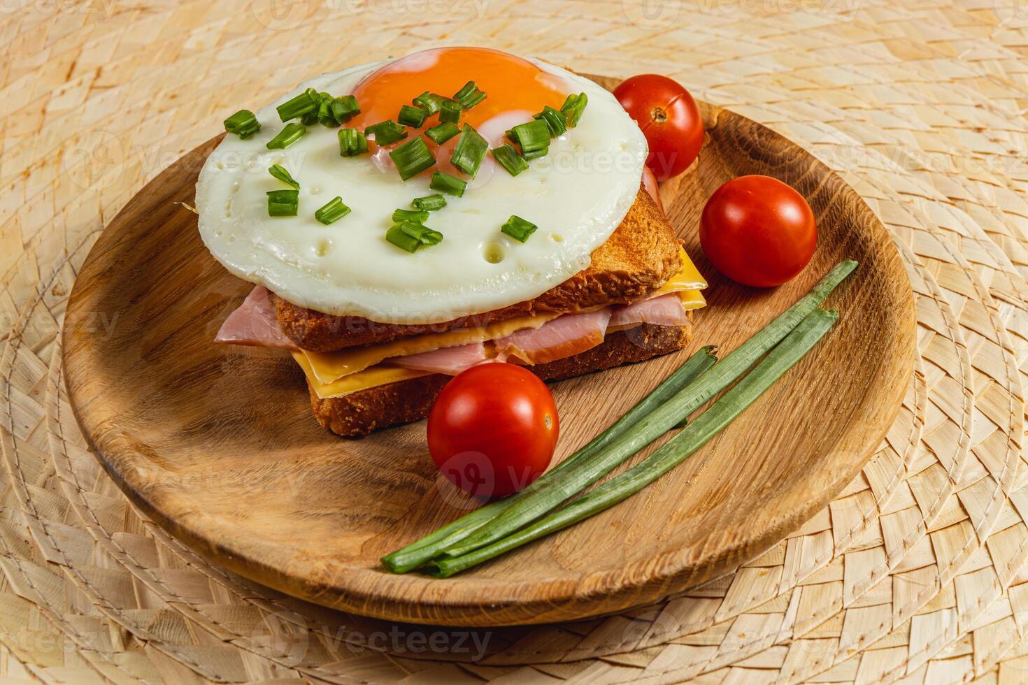 Delicious breakfast sandwich with fried egg, ham, and cherry tomatoes photo