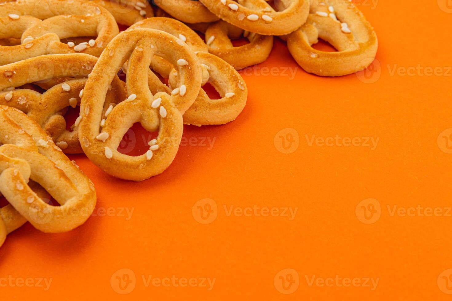 Crunchy pretzels on vibrant orange background for snack lovers photo