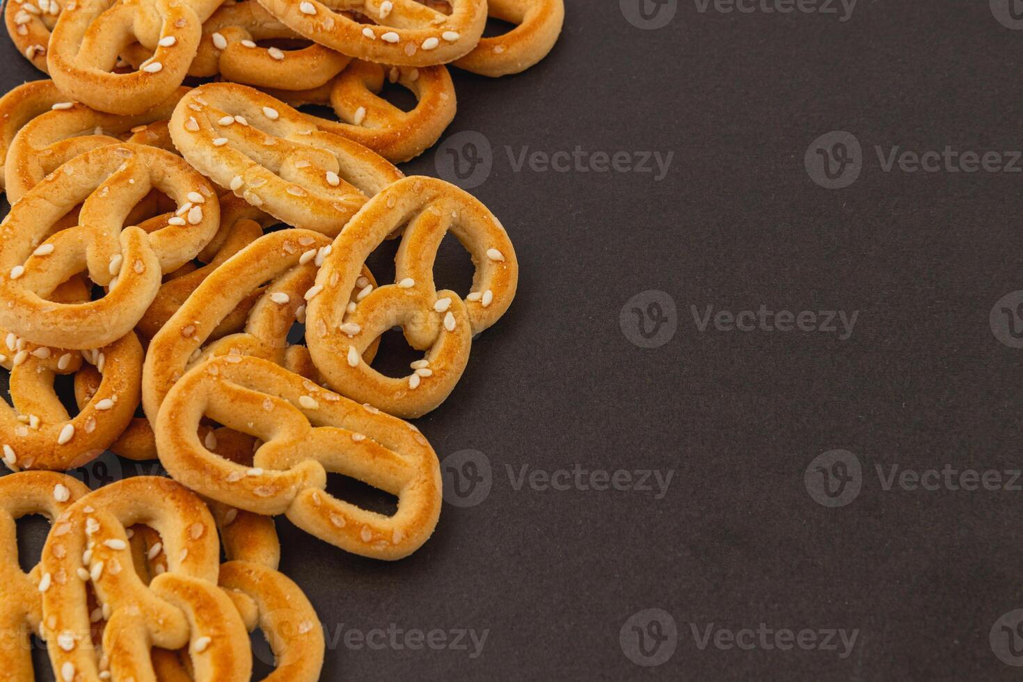 Delicious pretzels with sesame seeds arranged on a dark background photo