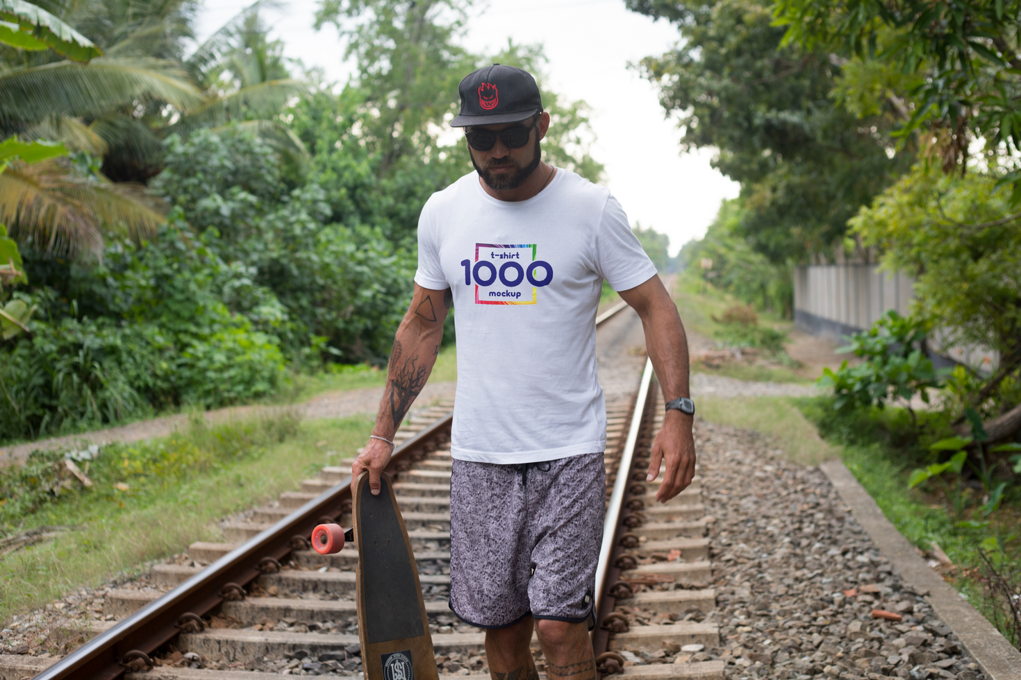 Man with Longboard on Train Tracks Wearing 1000 Monkeys T-shirt psd