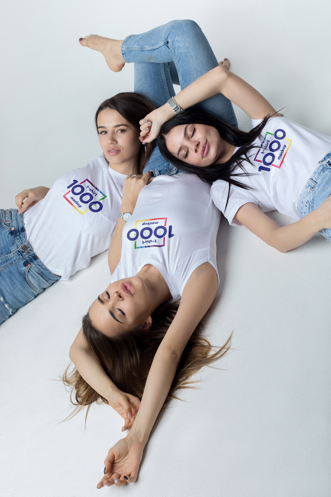 Three Young Women Lying Down, Wearing Matching White T-shirts with a Logo psd