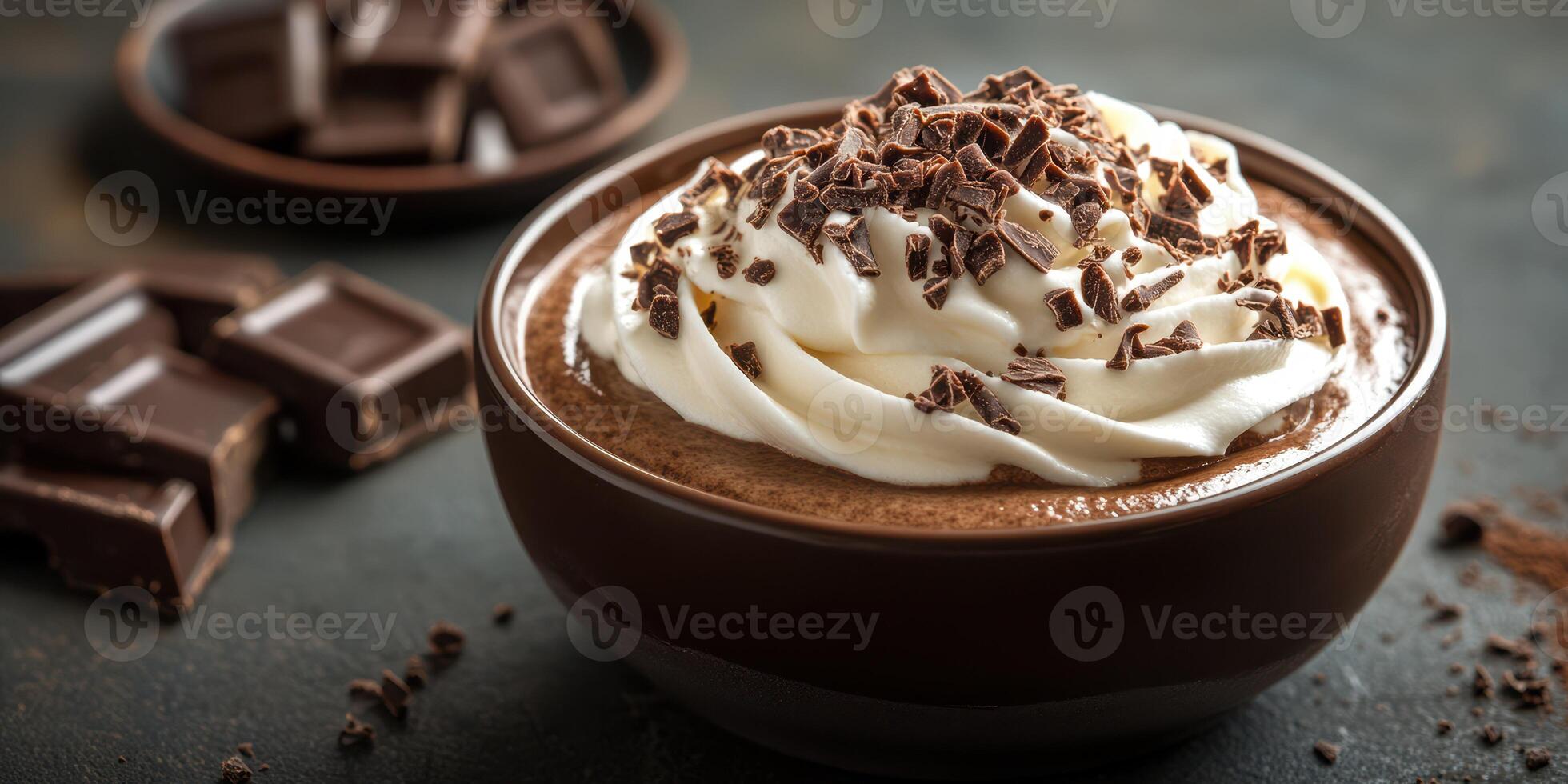 Rich chocolate mousse topped with whipped cream and chocolate shavings served in a bowl alongside dark chocolate pieces photo