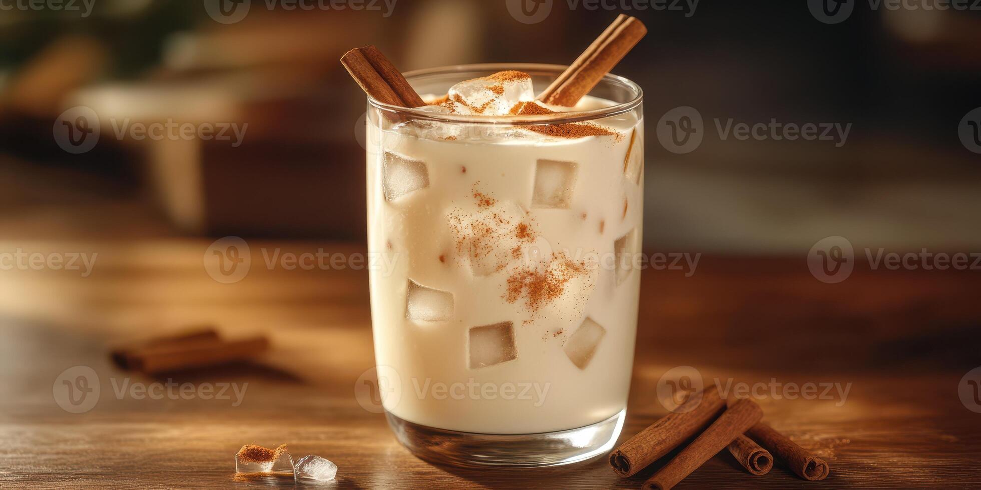 Creamy cinnamon iced drink served in a glass with ice and garnished with cinnamon sticks on a wooden table photo