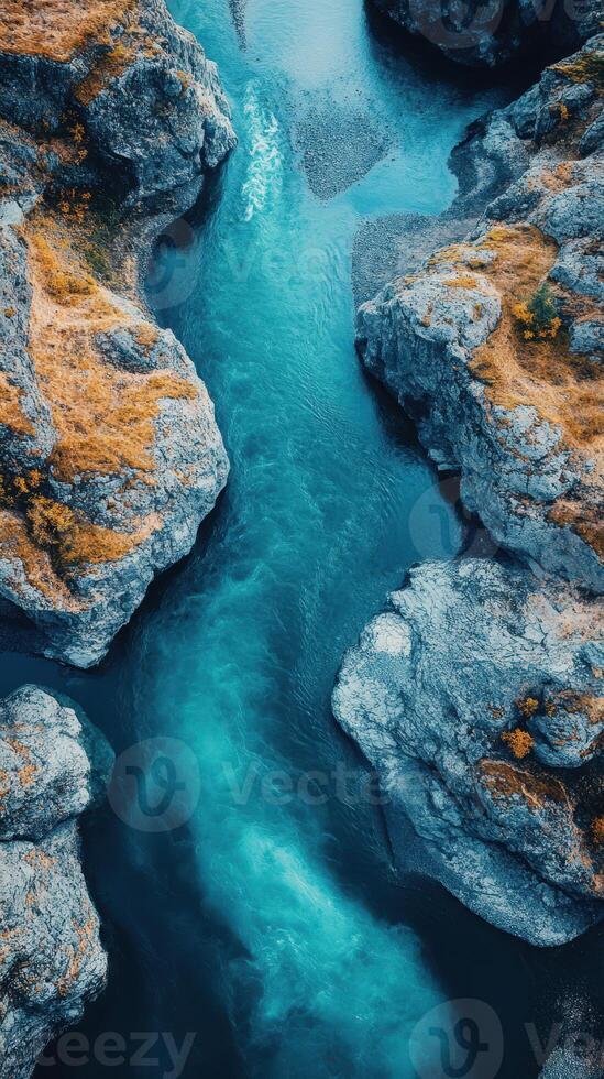 Vibrant blue river flows between rocky cliffs in a serene landscape view from above at sunset photo