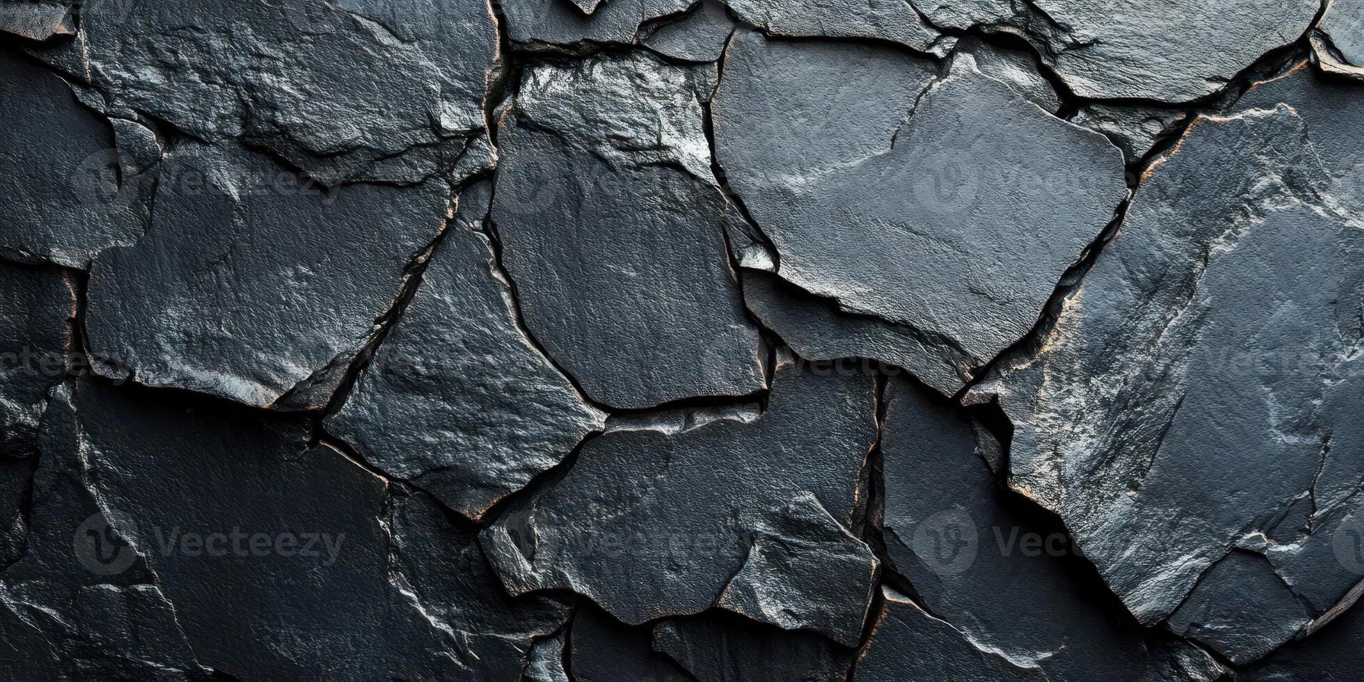 Textured black slate rocks arranged closely on a surface in a natural layout created by geological processes photo