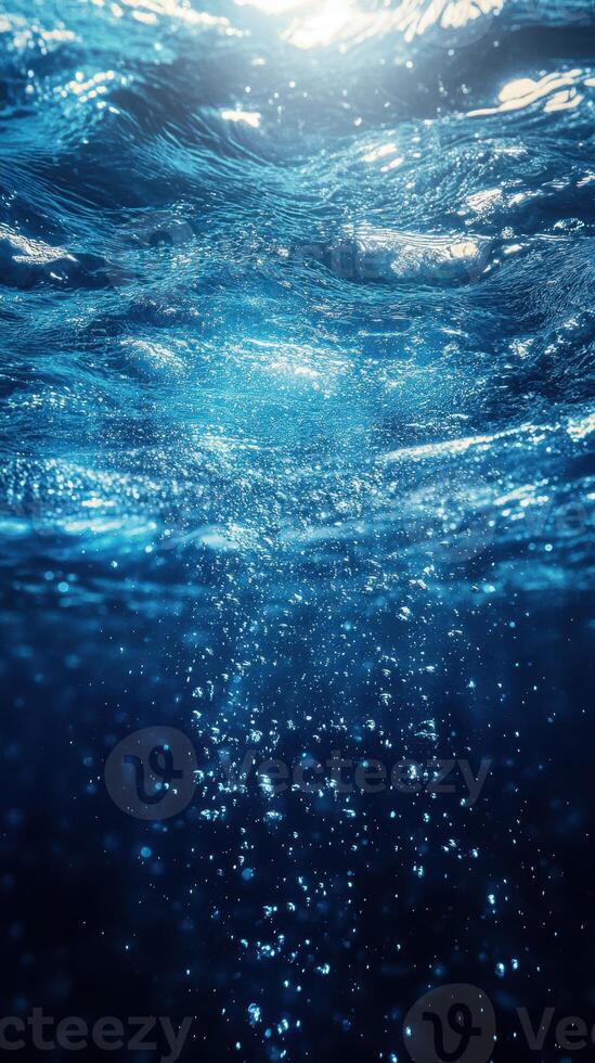 Bubbles rising through crystal clear water illuminated by sunlight at midday photo