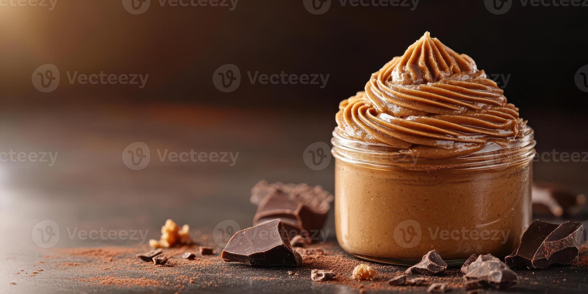 Creamy nut butter in a jar with chocolate pieces and cocoa powder on a dark background photo