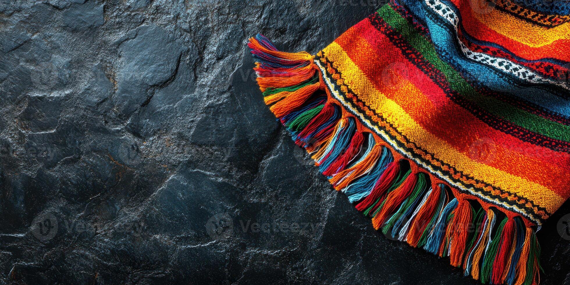 Colorful woven textile draped over dark stone surface showcasing intricate patterns and vibrant hues photo