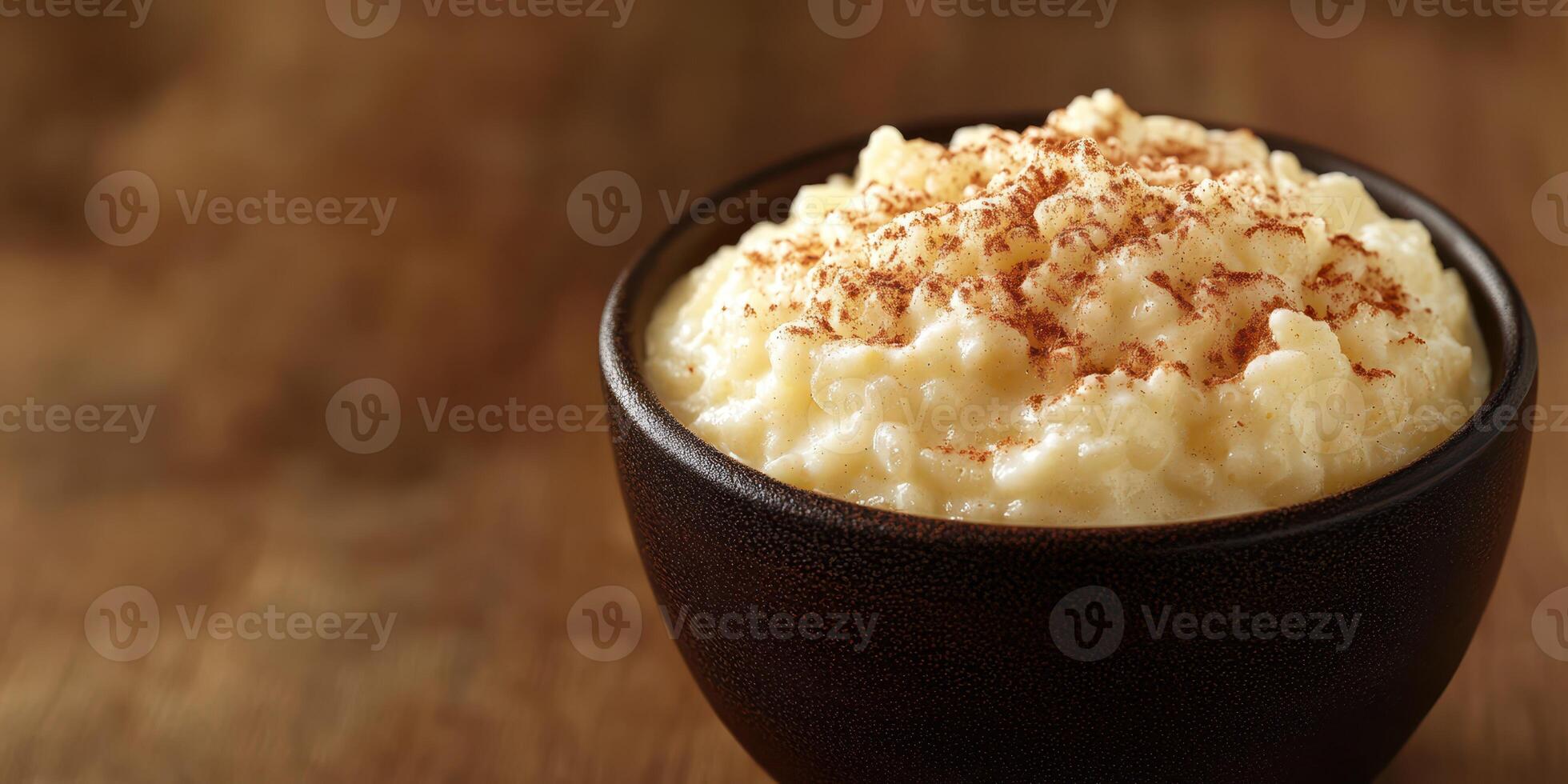 Creamy rice pudding topped with cinnamon served in a rustic bowl on a wooden table photo