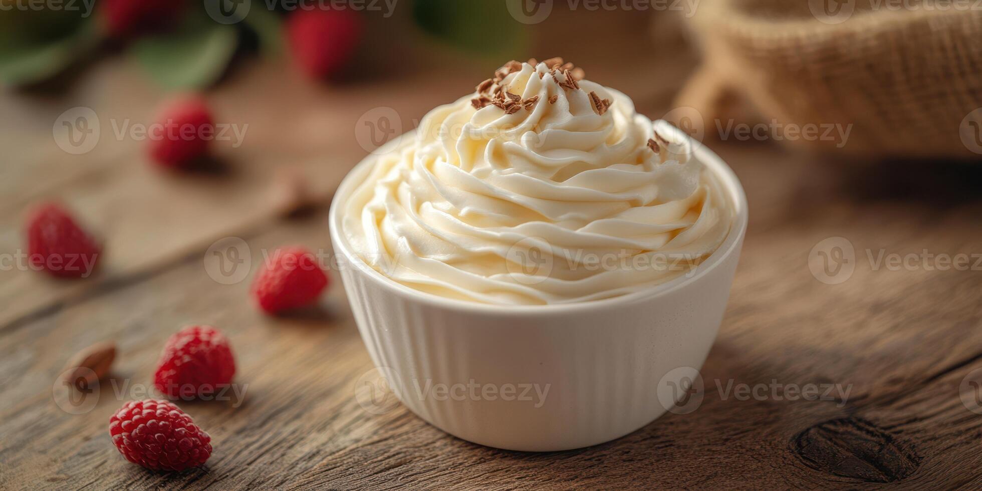 Creamy dessert topped with whipped cream and chocolate shavings beside fresh raspberries on a rustic wooden table photo